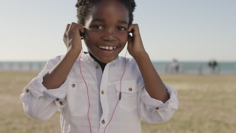 retrato en primer plano de un animado niño afroamericano feliz con auriculares escuchando música bailando juguetón en el parque