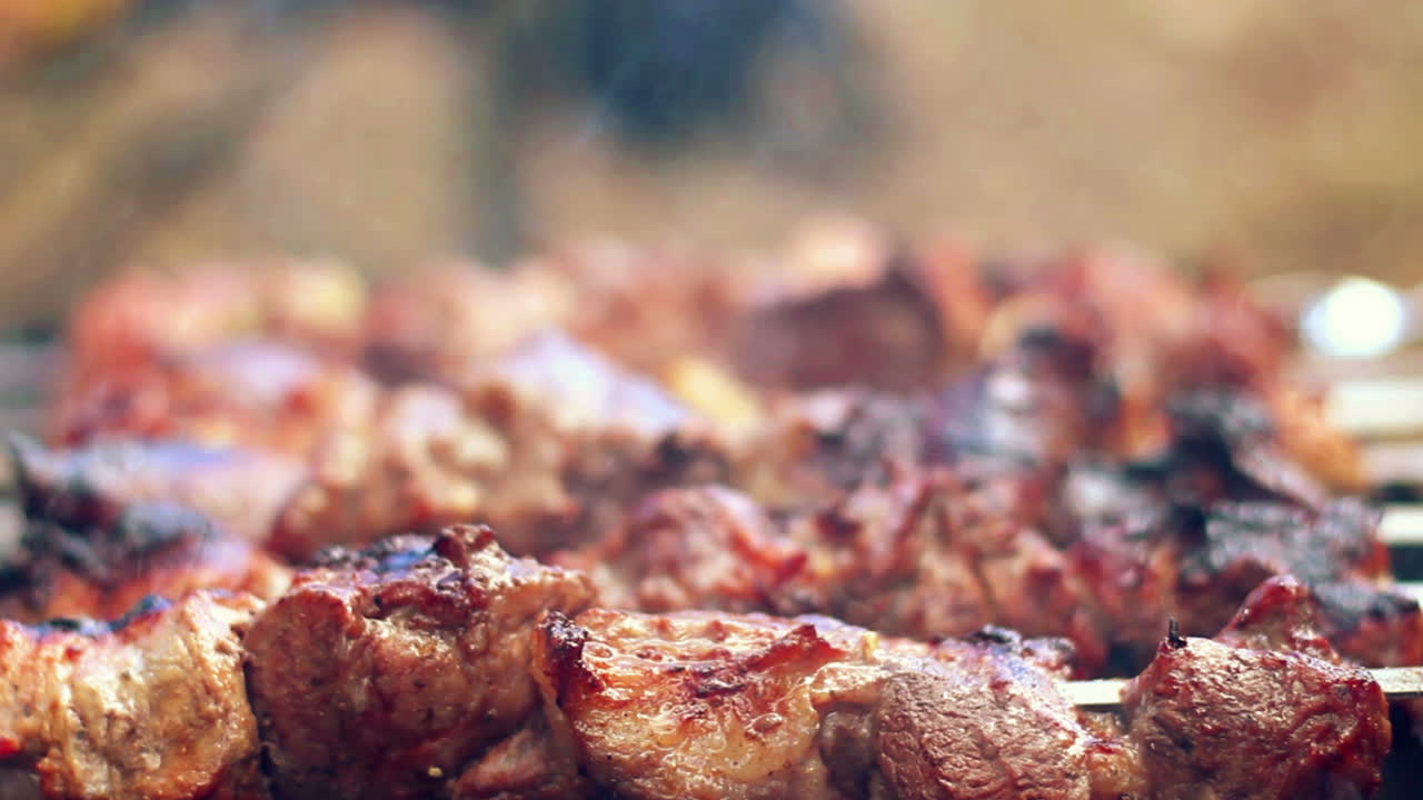 Grelhando carne de churrasco em carvão vegetal. Homem vira espetos. Alimentos grelhados.