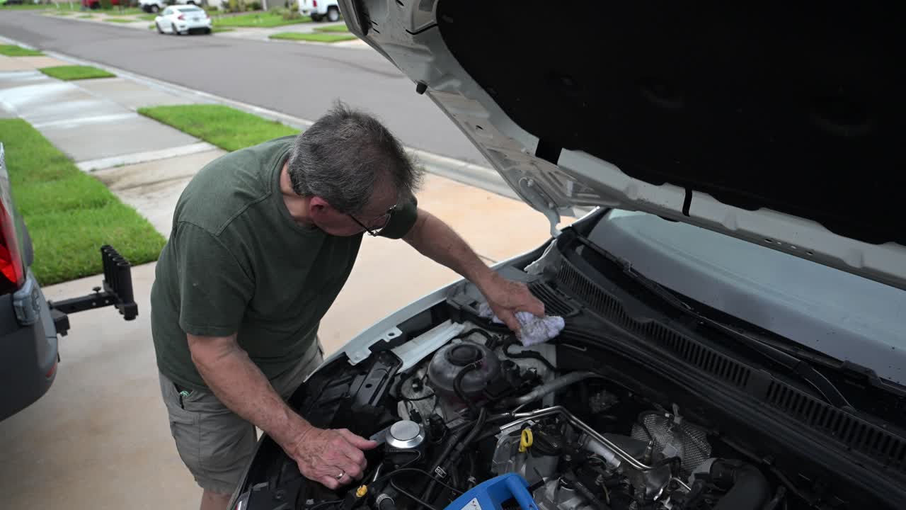 el abuelo mantiene su coche limpiando la suciedad del motor en su preciado coche