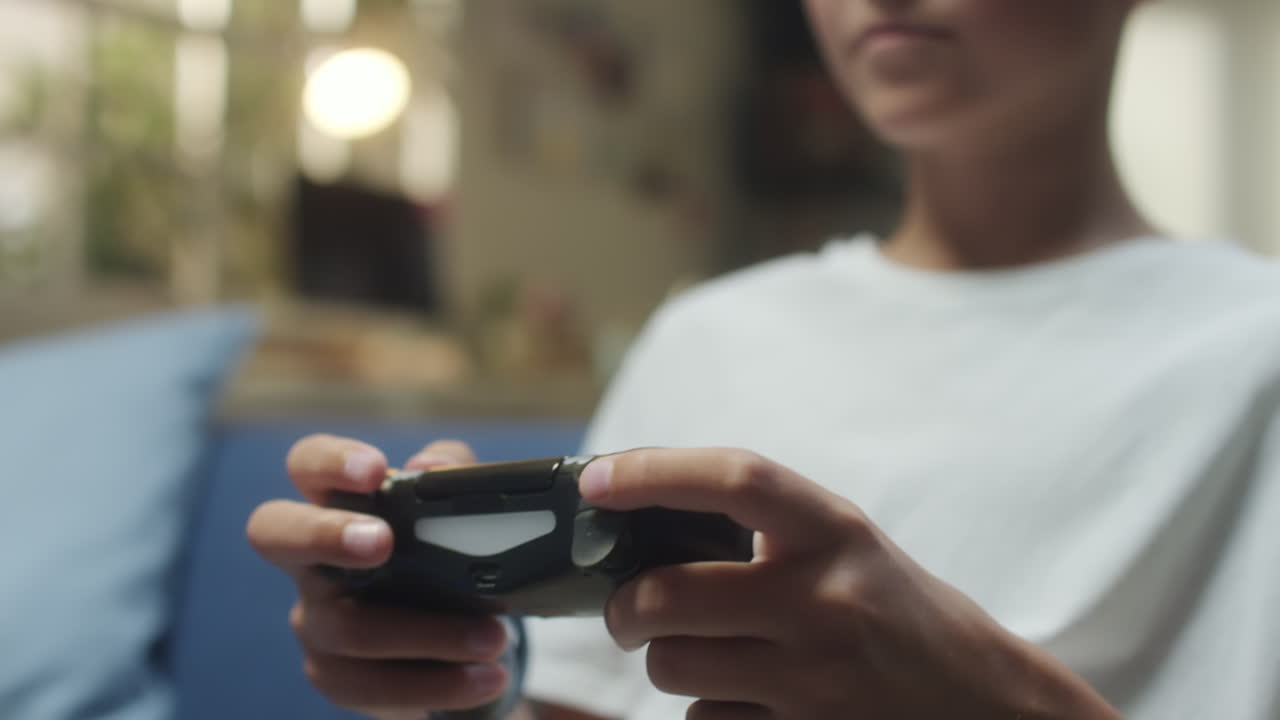 Close-up of a person's hands holding a video game controller while playing
