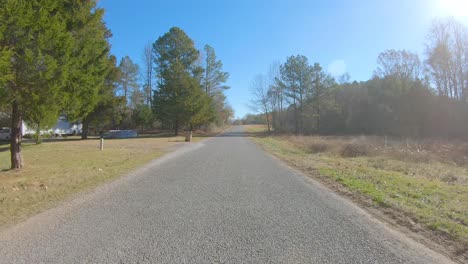 pov conduciendo una carretera rural del condado a través de una zona boscosa en el norte de mississippi, ee.uu. en un soleado día de invierno