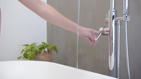 adjusting water temperature, woman testing water flow in modern bathroom spa