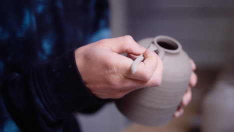 potter puts the finishing touches on clay vase in her worksop close-up on vase