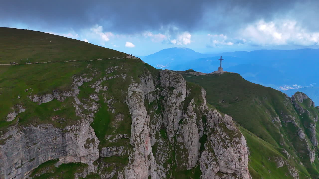 Spectacular cliffs covered with grass on top. Hikers walk by the stunning rocks. Approaching the Heroes' Cross close to the Caraiman peak in the Bucegi Mountains, Romania