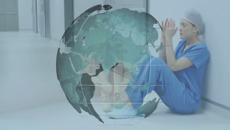 Animation-of-rotating-globe-and-wooden-toy-over-tired-caucasian-female-doctor-sitting-in-corridor