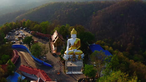 golden statue of sitting buddha in wat phra that doi kham temple