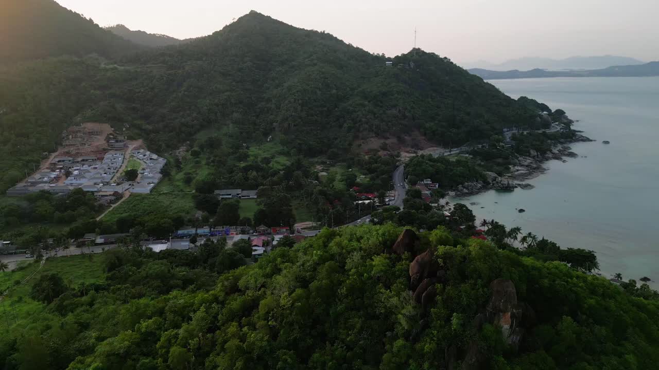 retiro aéreo capturando la costa de koh samui durante una tranquila puesta de sol revela casas a lo largo de la ladera