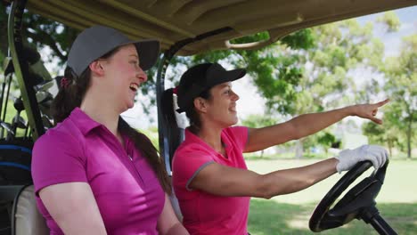dos mujeres caucásicas jugando al golf montando un carrito de golf hablando y riendo