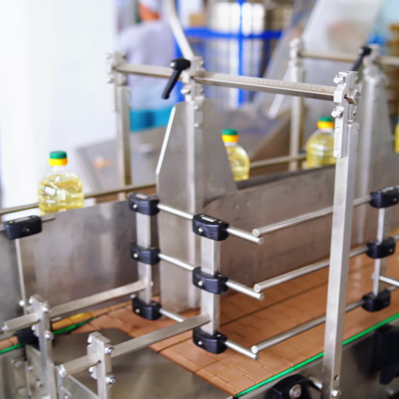 Modern factory of food oil production. Row of full plastic bottles of oil on a conveyor line. Fresh sunflower oil inside the automated manufacture.