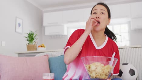 video of exited asian woman eating chips and watching match in tv