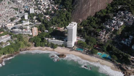 Seitlicher-Schwenk-Aus-Der-Luft,-Der-Den-Strand-Von-Vidigal-Mit-Der-Elendsviertelgemeinde-Und-Dem-Berg-„Two-Brothers“-Im-Hintergrund-Zeigt