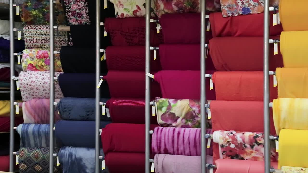 primer plano de coloridos rollos grandes de muestras de tela organizadas verticalmente: toma interior con movimiento panorámico de la cámara y enfoque nítido