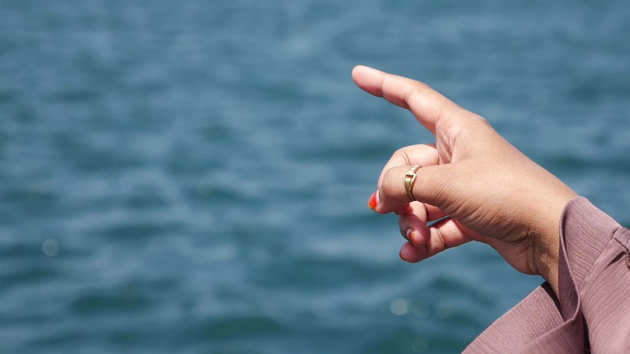 바다를 가리키는 여자의 손.