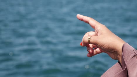 la mano de una mujer apuntando hacia el océano.