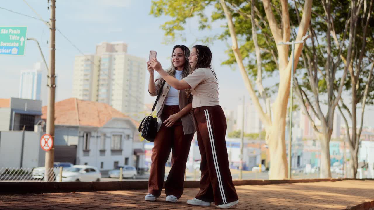Two Young Women Taking a Selfie on a City Street