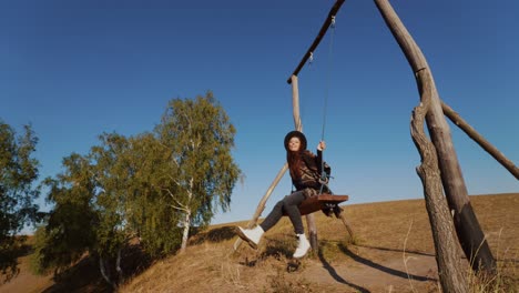 woman swinging on a wooden swing in a sunny autumn landscape