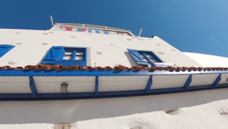 toma en órbita del marco de la ventana azul del edificio blanco con restaurante vacío frente al mar en bodrum