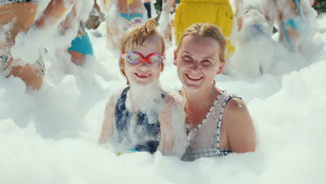 A-Young-Girl-With-A-Child-Fully-Wrapped-In-Foam-Looks-At-The-Camera-And-Smiles-Portrait