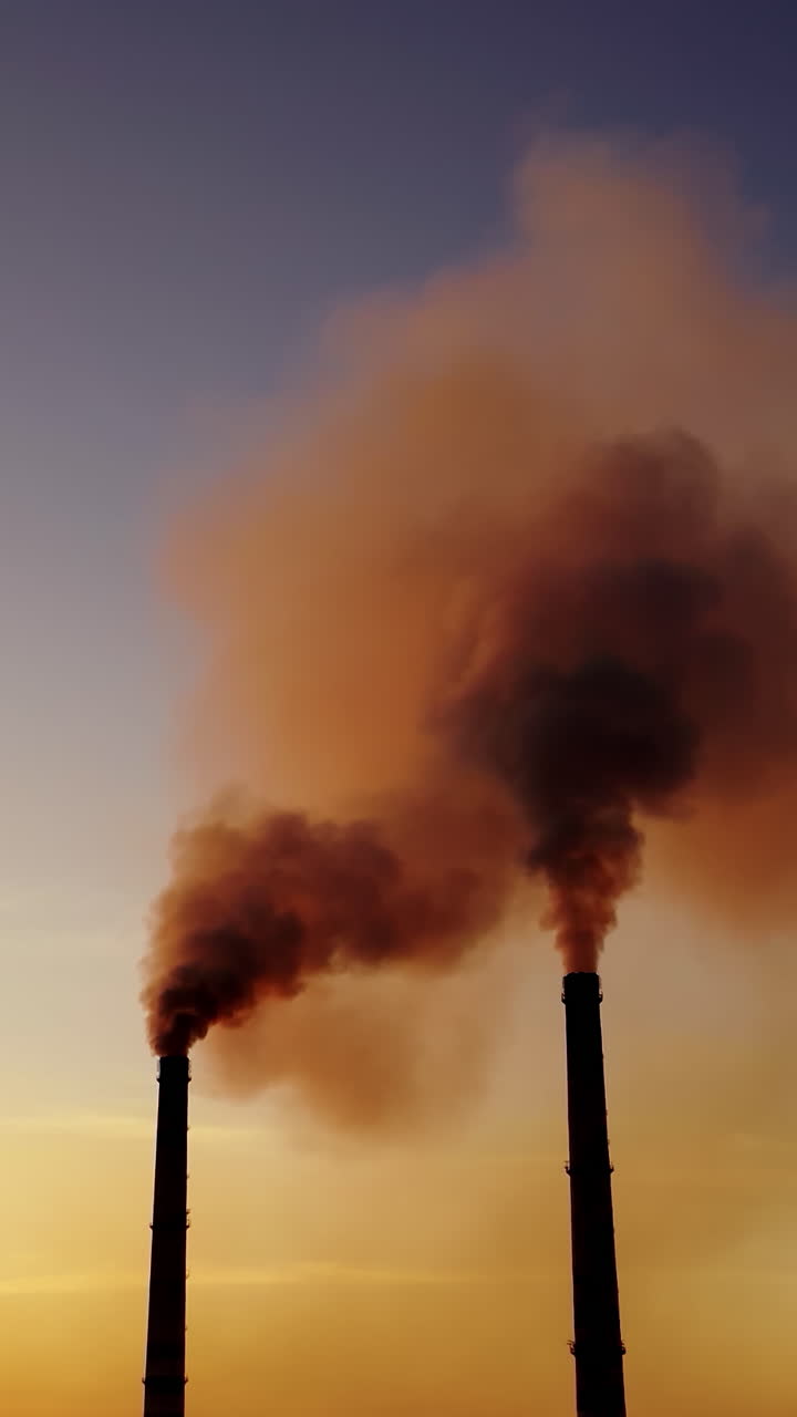 Plant pipe with smoke. Aerial view of high chimney pipes with grey smoke from power plant. Vertical video
