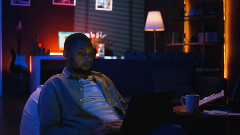 vertical video african american casual man solving daily tasks on his laptop at home