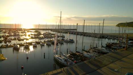 aerial drone orbit over beautiful ocean harbor sunset with ships moored at docks