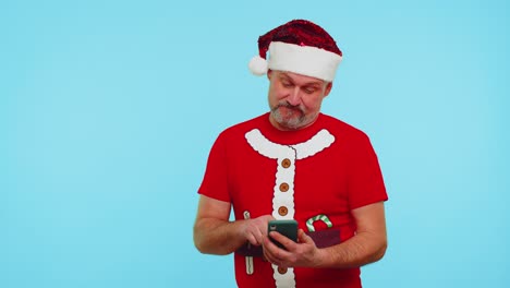 Man-in-Christmas-t-shirt,-hat-using-mobile-phone-typing-new-post-on-web,-shopping-online,-browsing