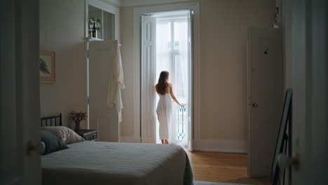 niña doméstica cortinas abiertas por la mañana en el interior. mujer anónima mirando por la ventana