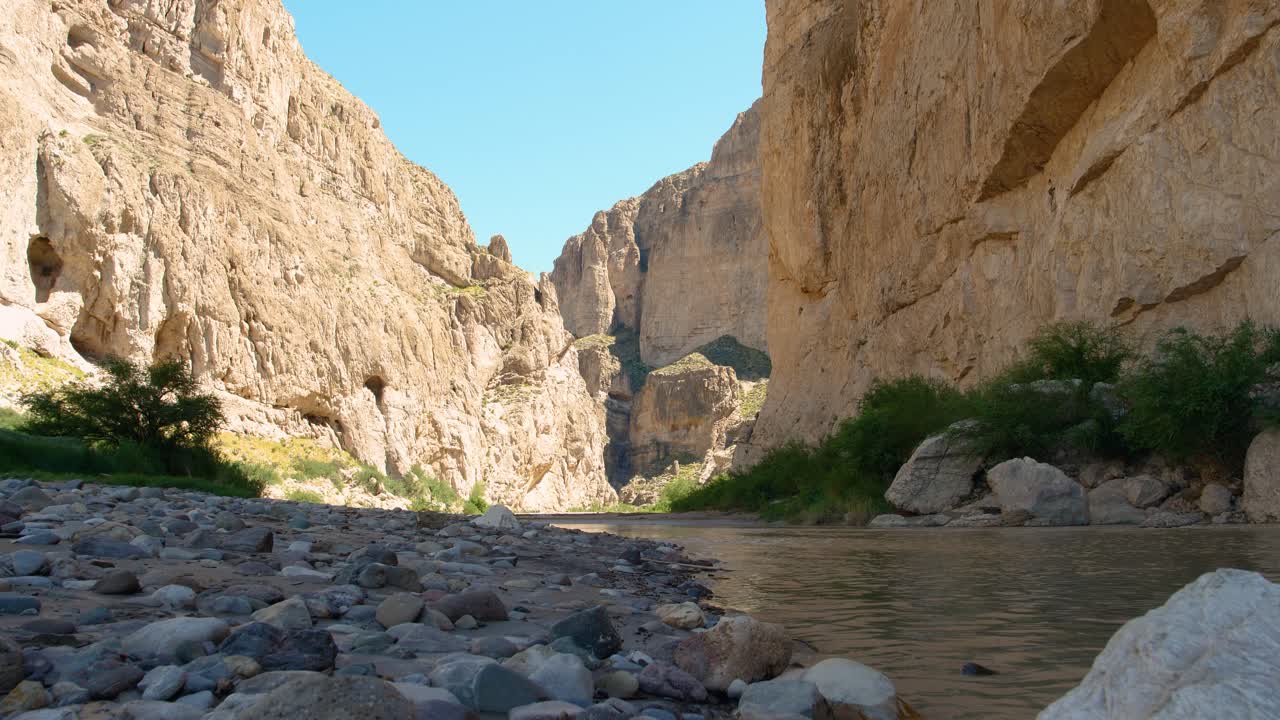Big Bend National Park - Rio Grande in 4K: Slow zoom from the river’s surface shows flowing water, pebbles on the U.S. side, and towering rock mountains on Mexico's side, marking the natural border.