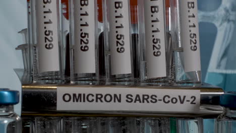 Primer-Plano-Inclinado-De-Una-Fila-De-Tubos-De-Ensayo-Etiquetados-Con-La-Nueva-Variante-Covid-19-Omicron,-La-Nueva-Mutación-Identificada-En-Sudáfrica-B