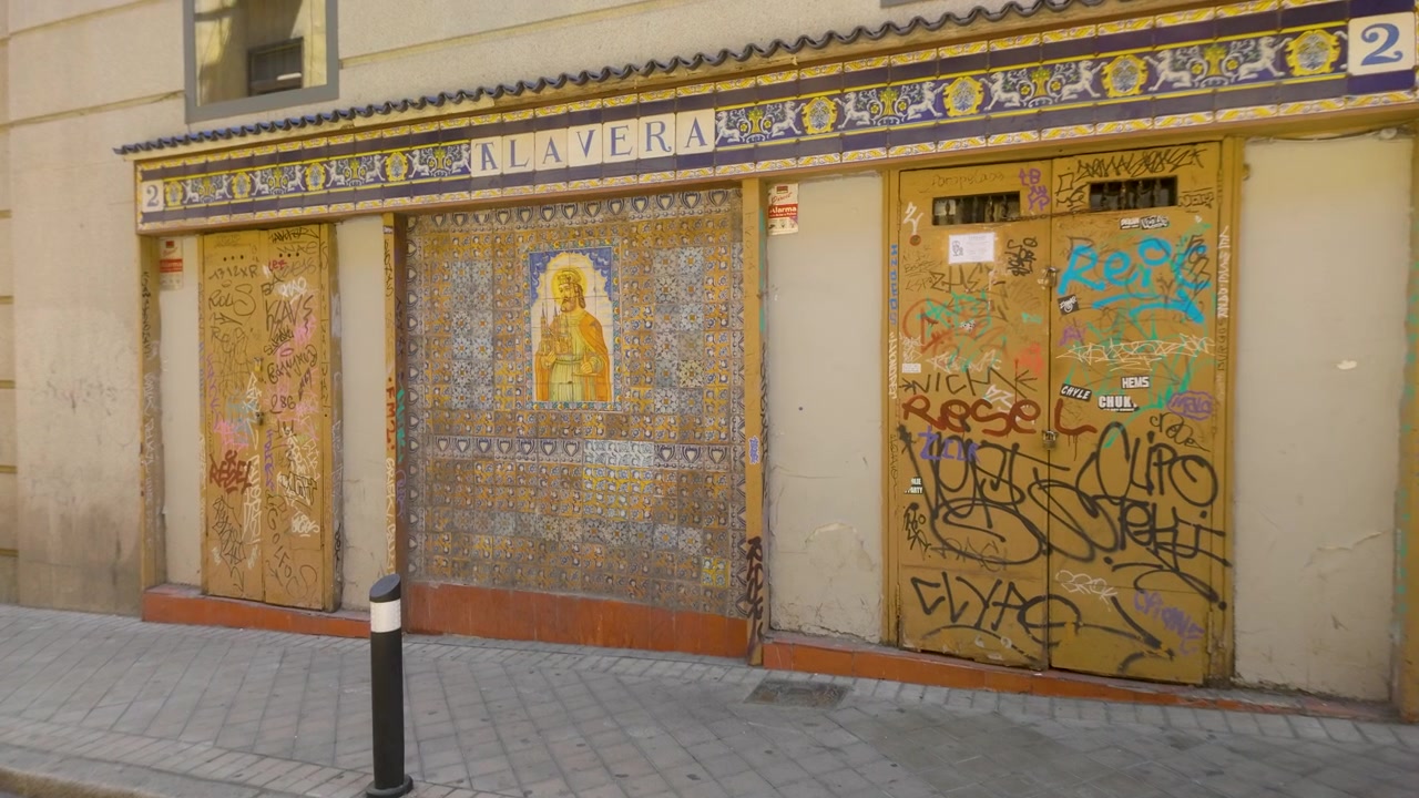 Madrid'de geleneksel seramik fayanslar ve modern şehir grafitileri içeren eski bir bina cephesinin detaylı görünümü, şehrin otantik kültürel kontrastını sergiliyor.