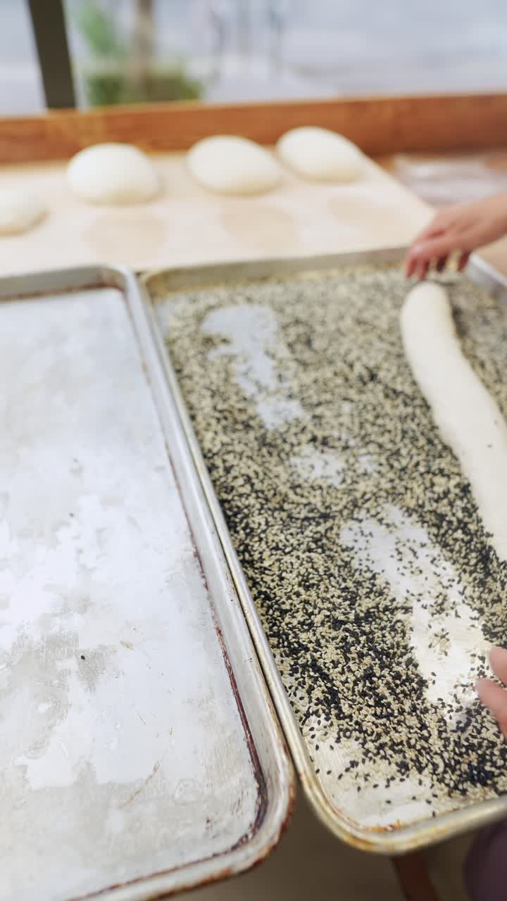 Baker preparing bread with sesame seeds