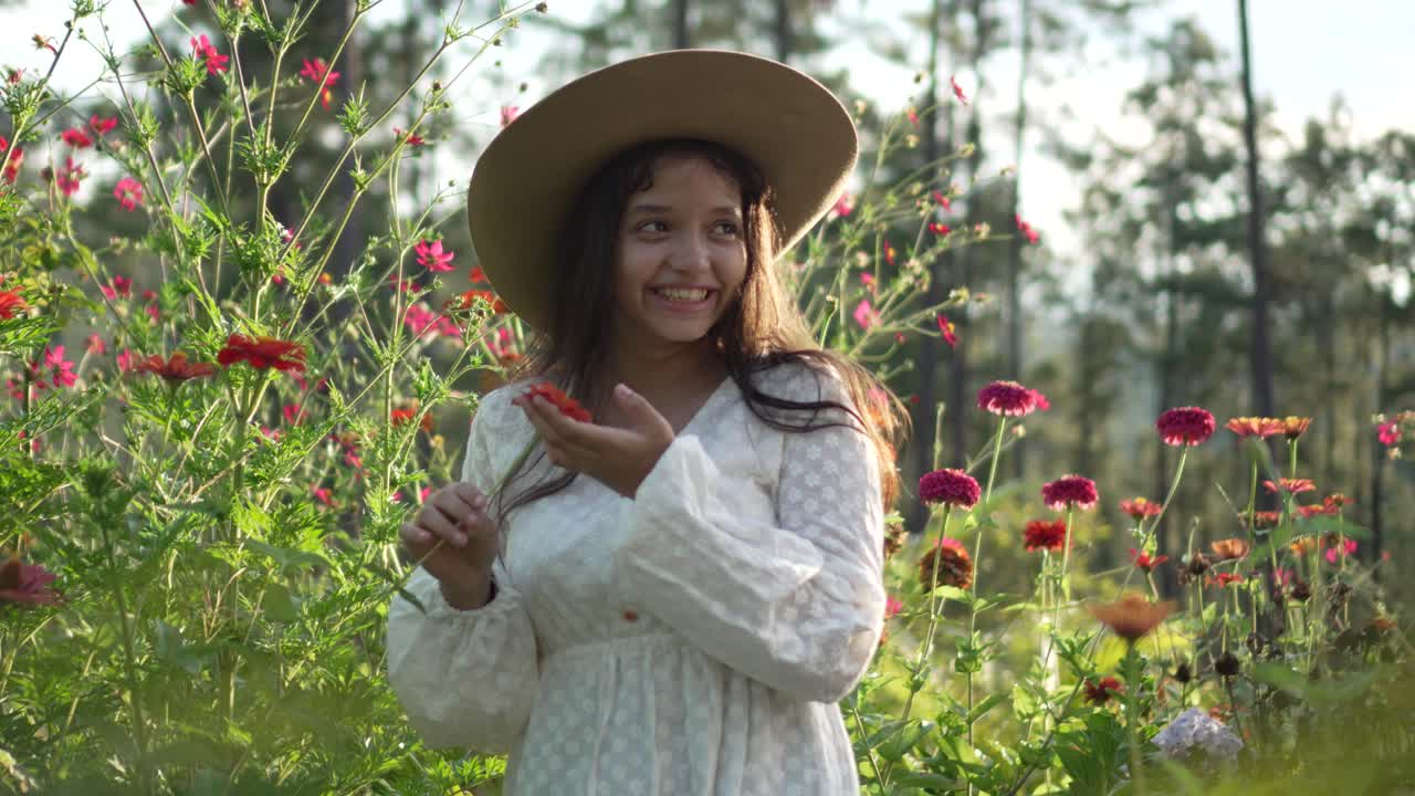 Bambina che indossa un cappello e un vestito bianco, sorridente e molto felice durante il tramonto