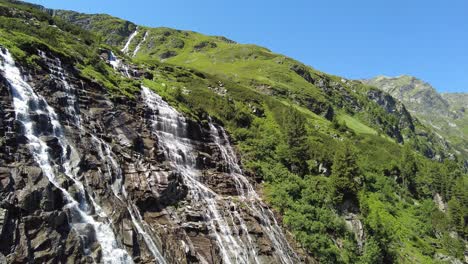 Flying-past-a-beautiful-waterfall-in-the-Alps-of-Austria,-Uttendorf-Weissee