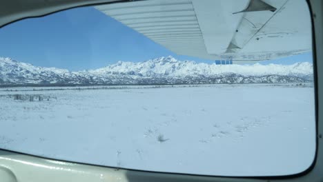 Flight-over-the-icy-waters-Cook-Inlet-in-Alaska-during-winter-with-vast-expanses-of-snow-covered-forests,-rivers,-valleys,-and-mountain-peaks-of-the-Chugach-Mountain-Range