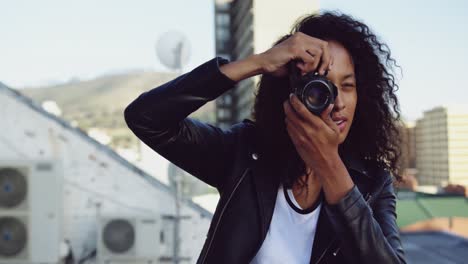 Fashionable-young-woman-on-urban-rooftop-taking-photos