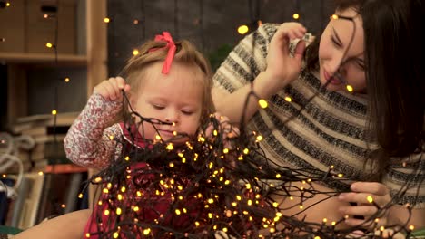 madre e hija jugando con luces de navidad