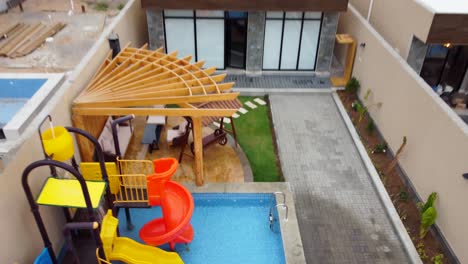tiro de dron de un patio trasero de la casa con una piscina y toboganes de agua, inclinación de carro inverso