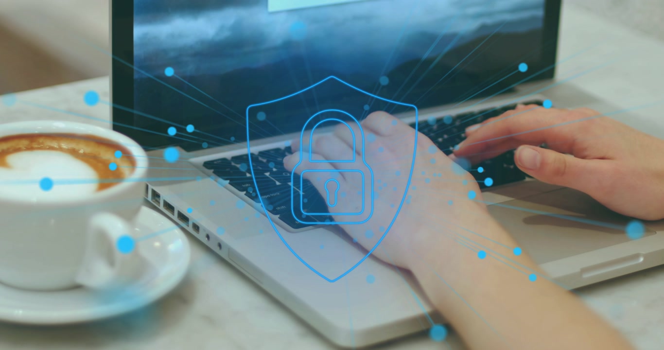 Adult hands typing keyboard beside cup causing blue bits swirling into shield padlock securing data