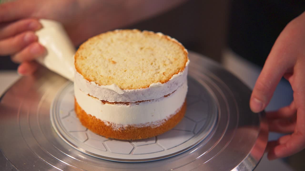 Mãos decorando um pequeno bolo de camadas com cobertura de creme branco
