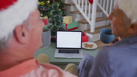 Back-view-of-caucasian-senior-couple-using-laptop-with-copy-space-at-christmas-time