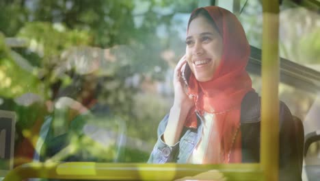 Animation-Einer-Glücklichen-Asiatischen-Frau-Im-Hijab,-Die-An-Einem-Sonnigen-Tag-Ihr-Smartphone-über-Gras-Benutzt