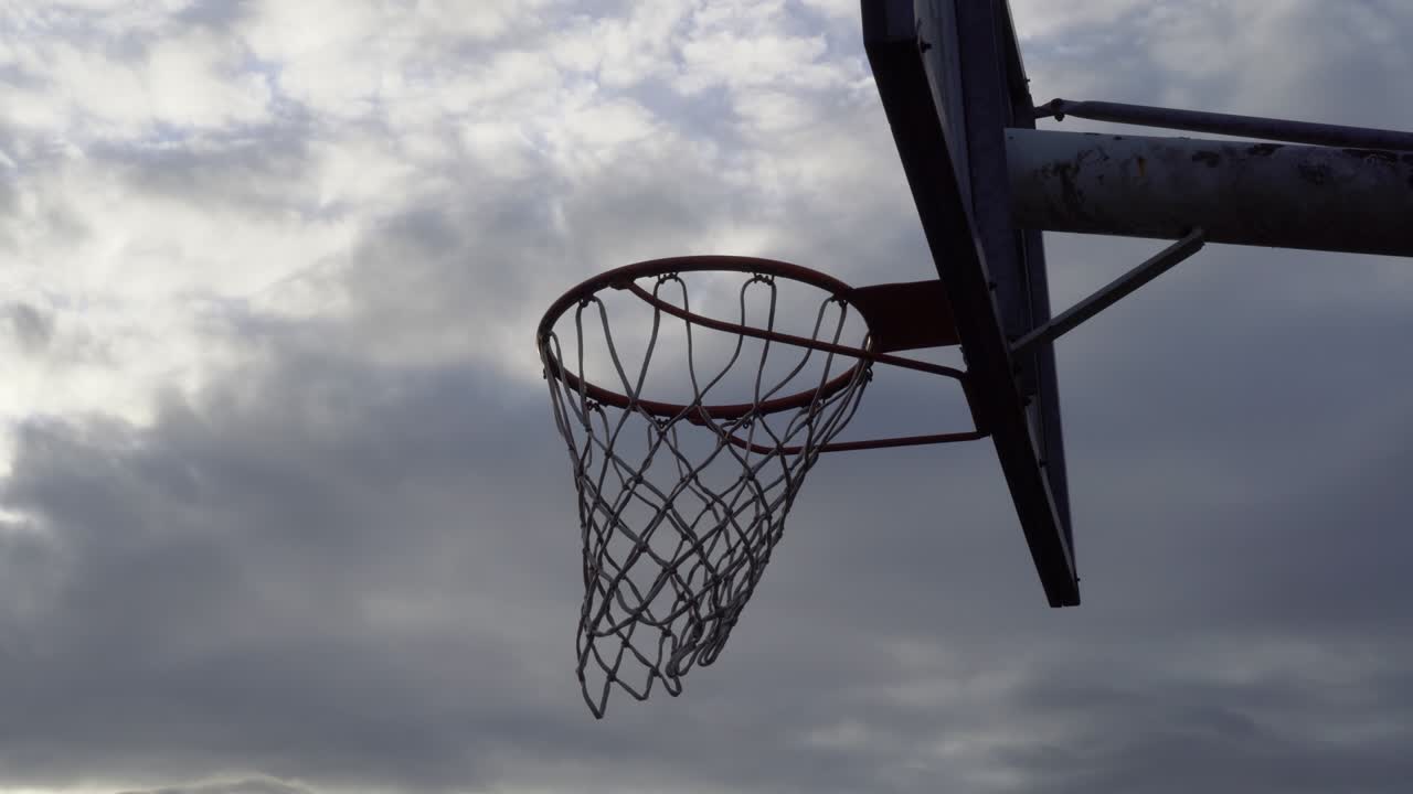 viejo backboard de baloncesto con aro y red en el cielo nublado