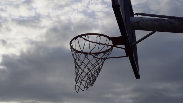 viejo backboard de baloncesto con aro y red en el cielo nublado