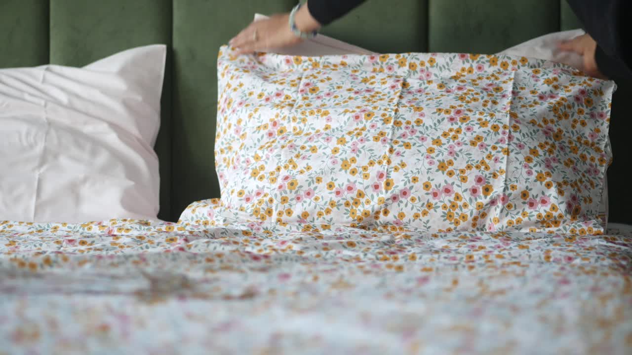 mujer haciendo la cama con sábanas florales