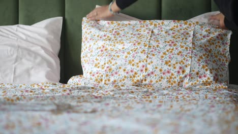 woman making the bed with floral sheets