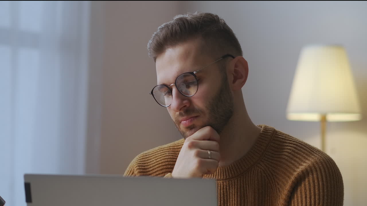 hombre aburrido con gafas está escuchando y mirando la pantalla durante una reunión en línea con colegas sentados en casa asintiendo con la cabeza retrato de hombre