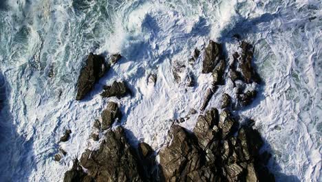 Antena-Arriba-Hacia-Abajo-De-Olas-Blancas-Del-Océano-Sobre-Rocas-De-Cornualles-En-Cornualles