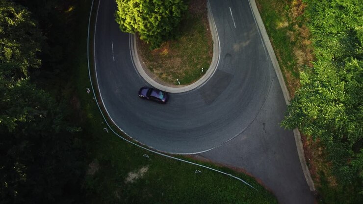 Ripresa con drone dell'auto che fa una curva stretta nella foresta verde in estate