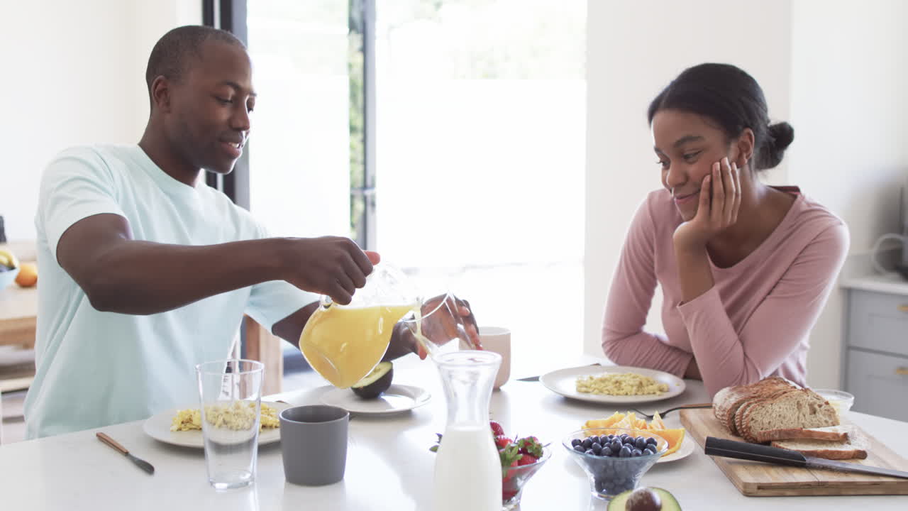 African American couple enjoys breakfast together at home in the kitchen