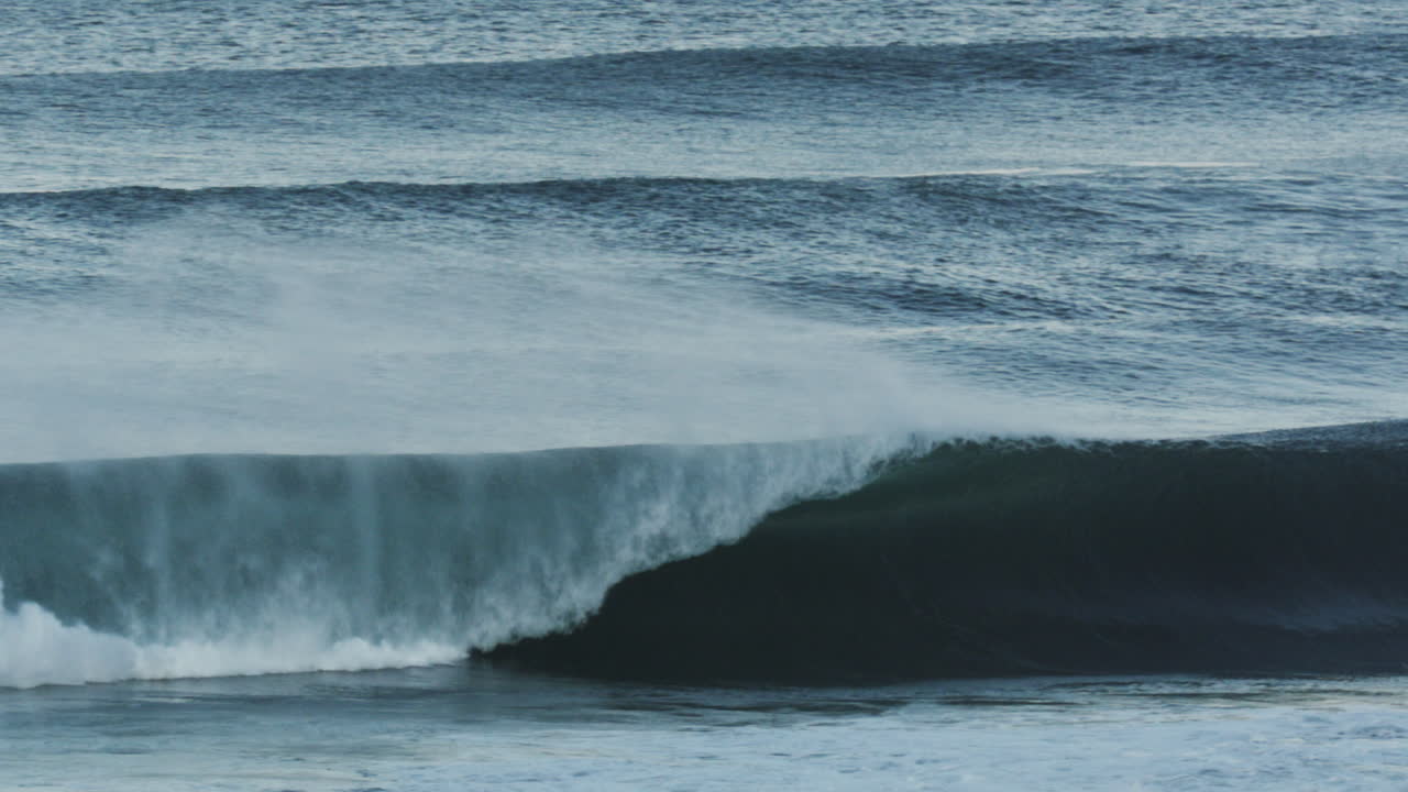Clean ocean break with bright white curl rolling toward shore